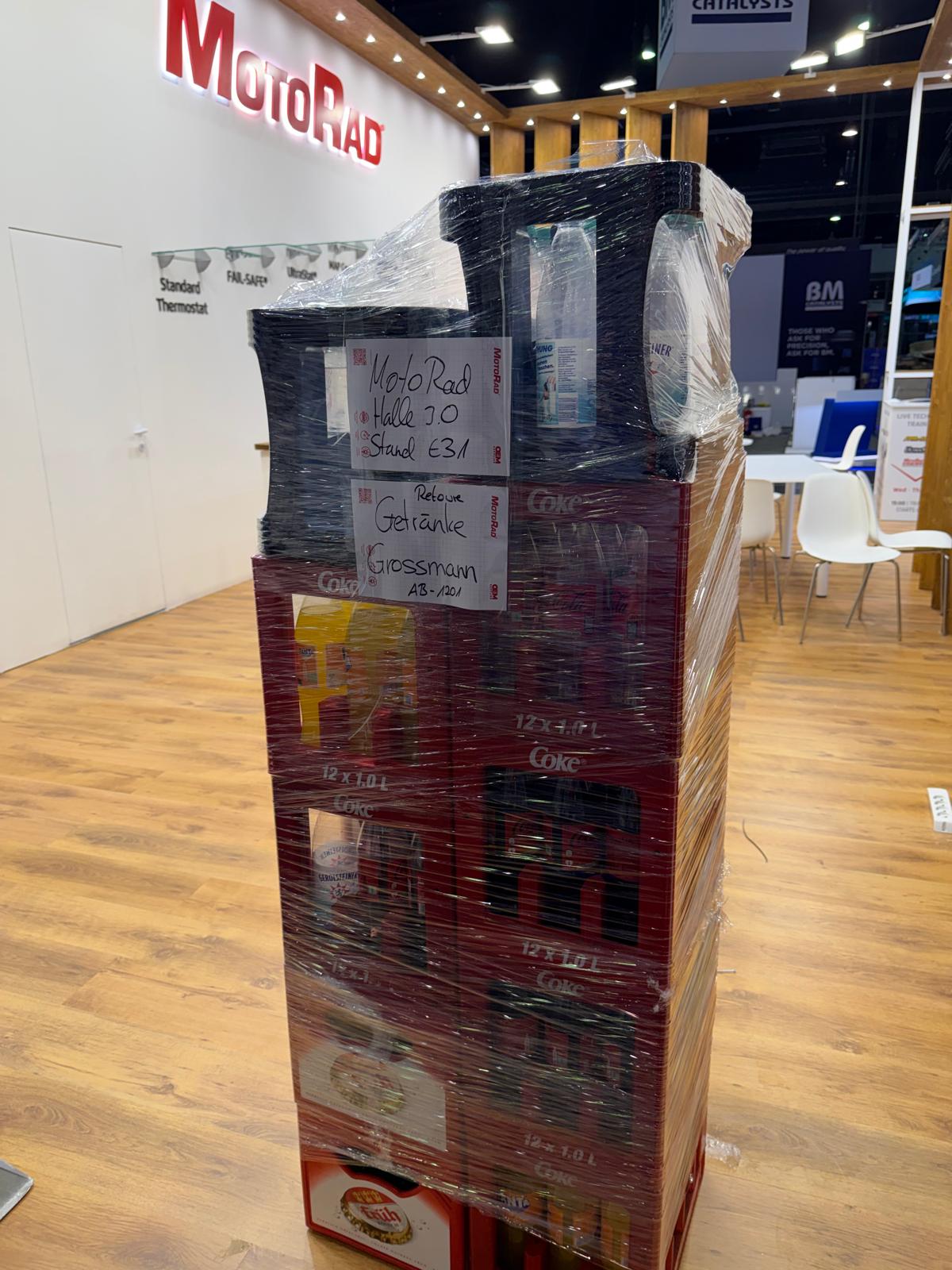 Mit Stretchfolie gesicherte Retourkästen und Leergut am Messestand, bereit zur Abholung nach Messeschluss.